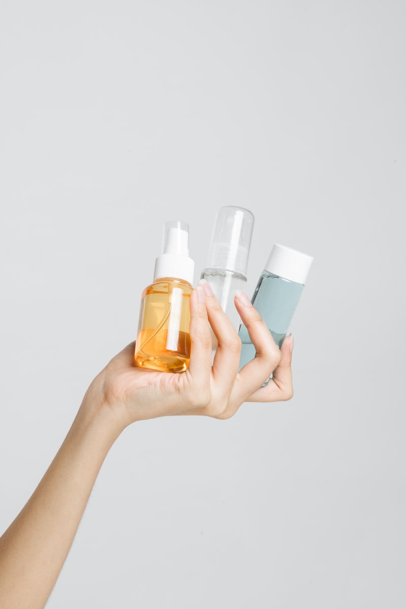 Female Hand Holding Different Cosmetic Bottles